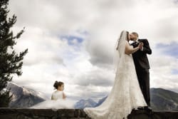 Bride And Groom Kissing Flower Girl Sitting On Ledge Banff Canada